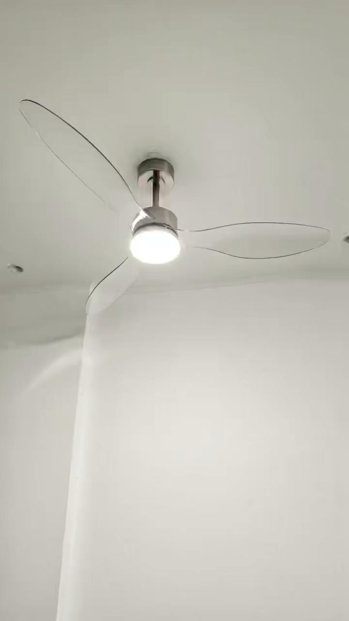 A silver-toned ceiling fan with three clear curved blades and an illuminated round center light, viewed from below.