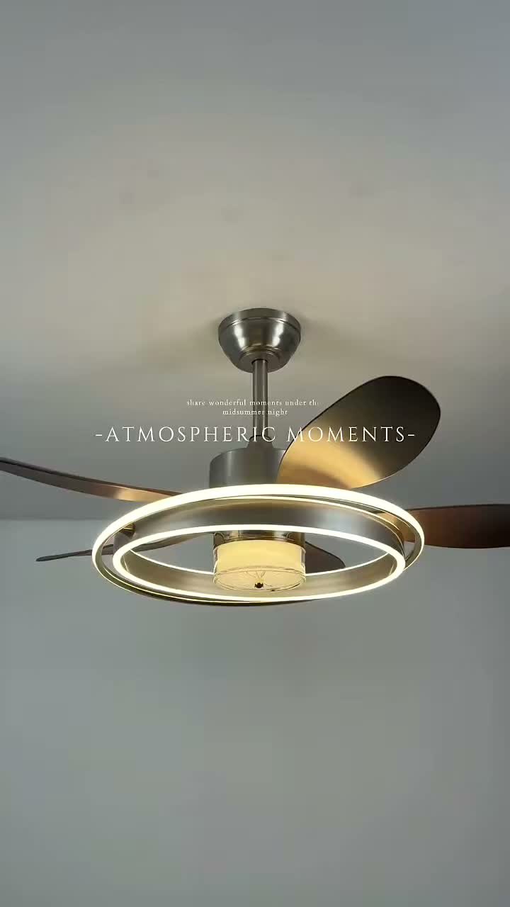 A ceiling fan light with dark blades, glowing ring edges, and a pale patterned center, shown from below.